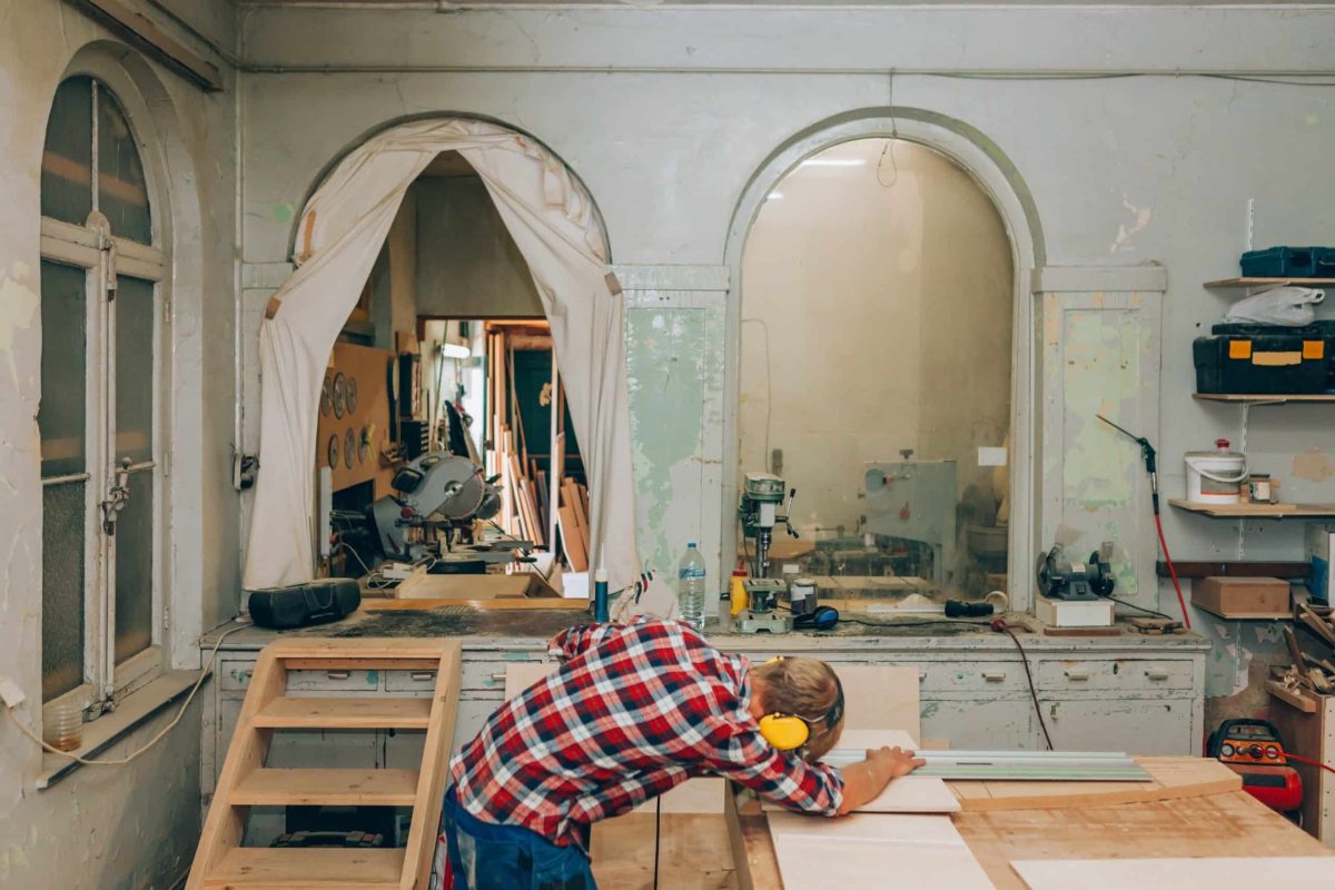 Designer man doing wood carpentry project using mowing saw inside workshop Designer man doing wood carpentry project using mowing saw inside workshop