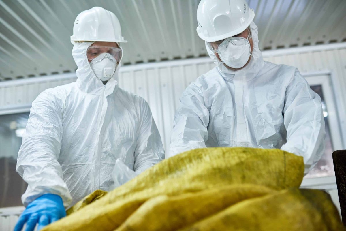 Workers Sorting Plastic on Recycling Plant Low angle portrait of two workers wearing biohazard suits working at waste processing plant sorting recyclable materials on conveyor belt
