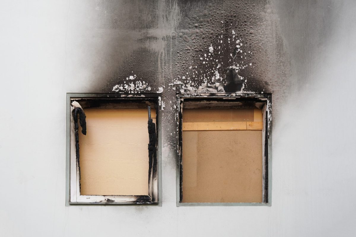 house or home fire - boarded up windows and burned facade blackened by soot of modern apartment building
